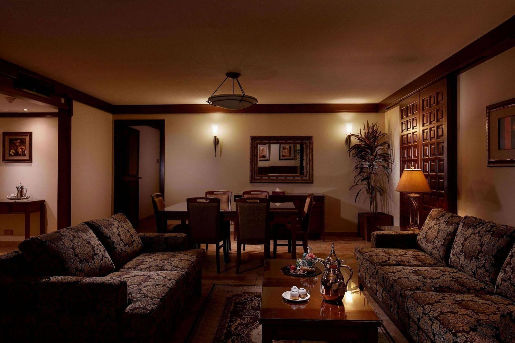 Makarem Ajyad Makkah Hotel Мекка Экстерьер фото The photo depicts a cozy living room setting. It features two patterned sofas facing each other with a wooden coffee table in the center. The room is softly illuminated, creating a warm atmosphere. On the walls, there are decorative elements, includi