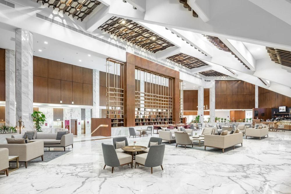 Makarem Ajyad Makkah Hotel Мекка Экстерьер фото The photo shows a spacious and modern hotel lobby. It features a high ceiling with an elegant design, incorporating wooden accents and contemporary lighting. The floor is made of white marble, creating a bright and open atmosphere. 

In the foregroun